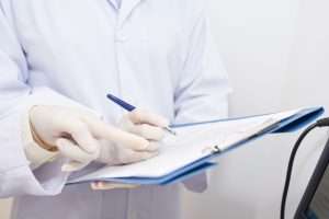 doctor filling out paper anesthesia record in patient's chart